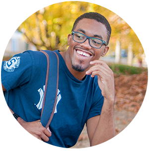 Student with glasses and book bag, smiling